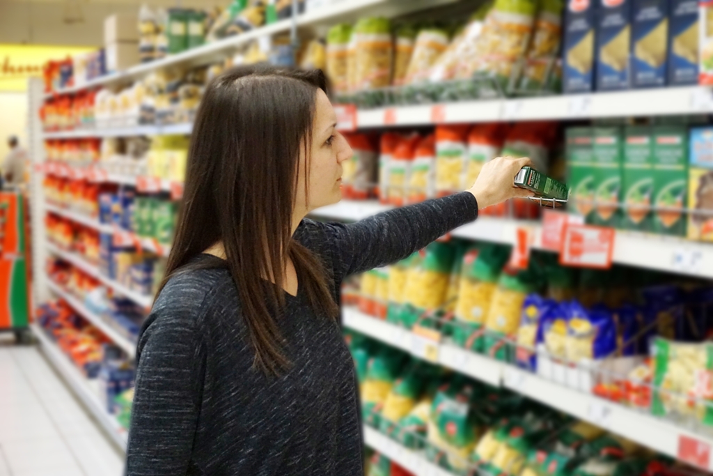 Frau nimmt Lebensmittel aus Supermartkregal / Einkauf