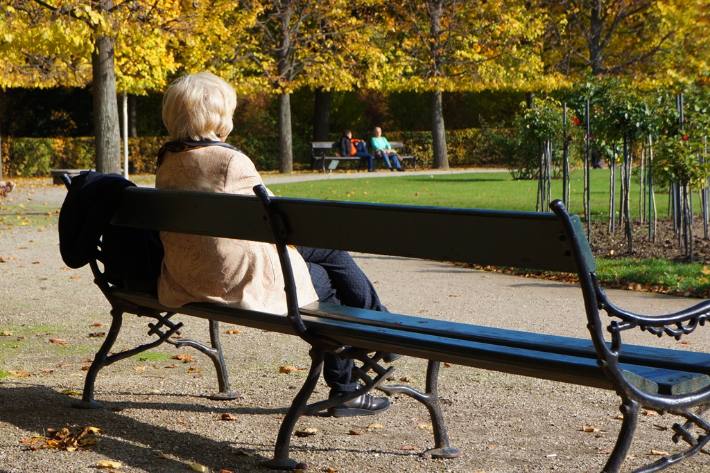 Herbst – Frau sitzt auf Parkbank