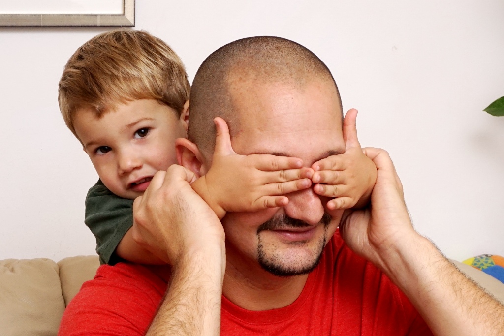 Kind hält Papa die Augen zu