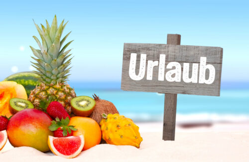 Frisches Obst am tropischen Strand mit Schild "Urlaub"